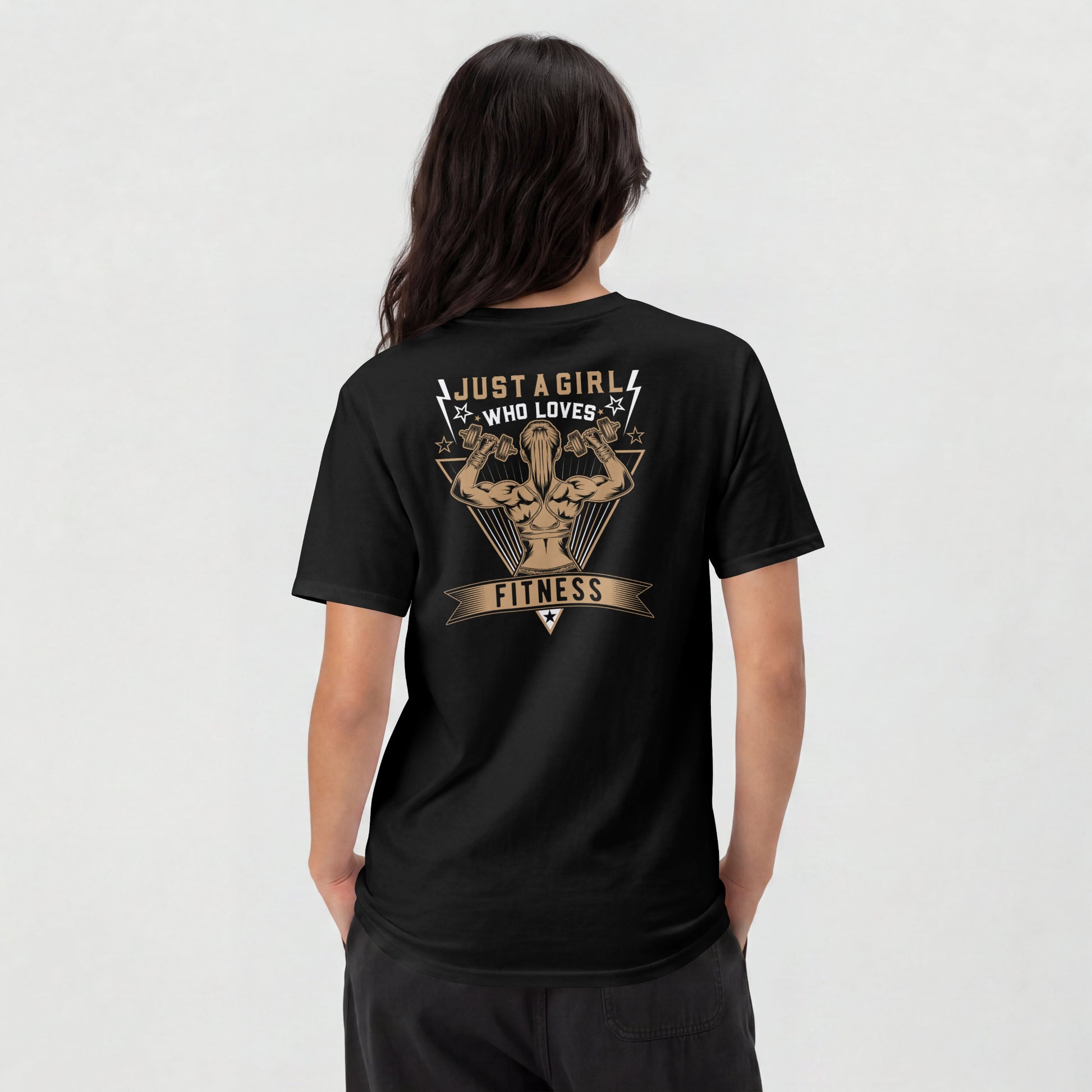A woman shown from the back wearing a black t-shirt with a large tan graphic on the back that reads 'JUST A GIRL WHO LOVES FITNESS' around an illustrated muscular figure.